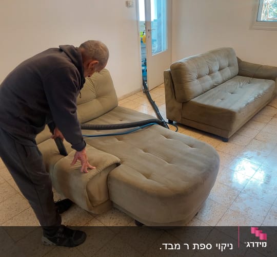 אדם מנקה ספה עם שואב אבק